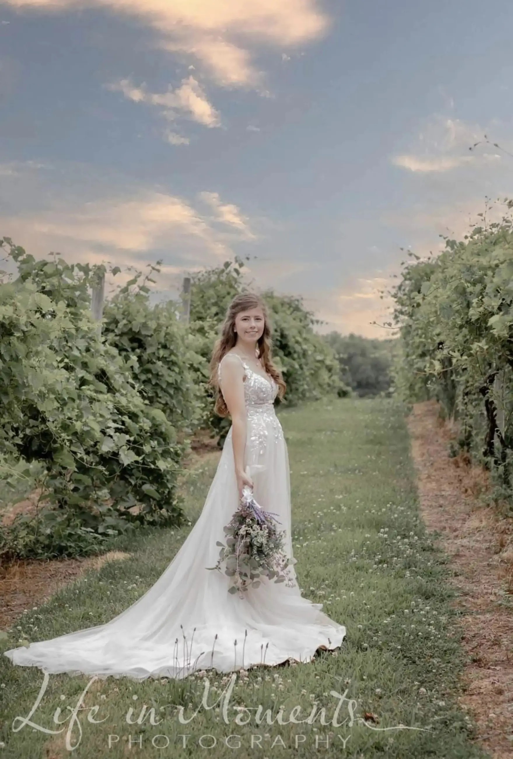 Woman is wearing an a-line bridal gown carrying a bouquet of flowers by her side