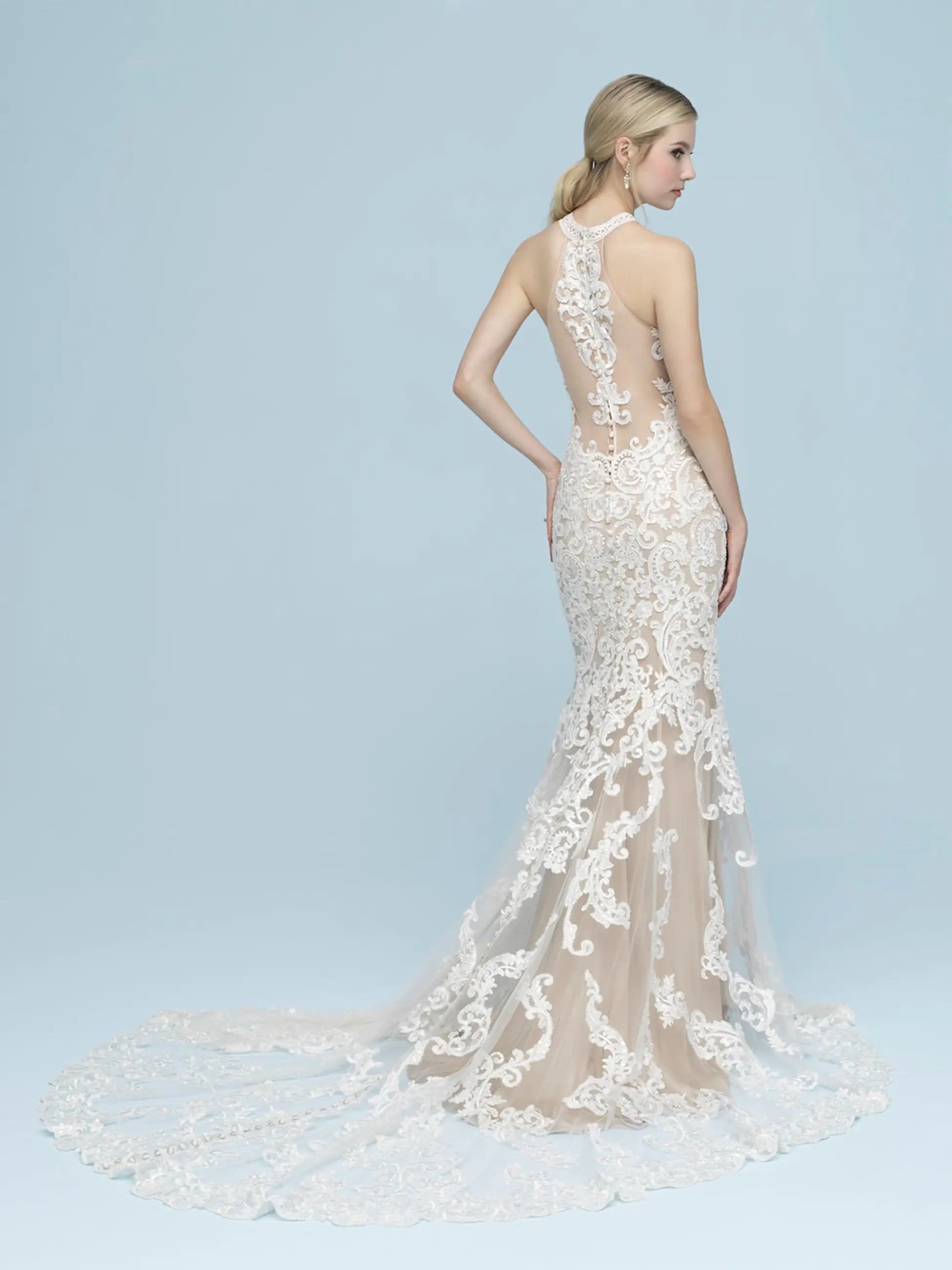 Model is wearing a high neckline sleeveless sheath bridal gown with intricate lace by allure bridals 