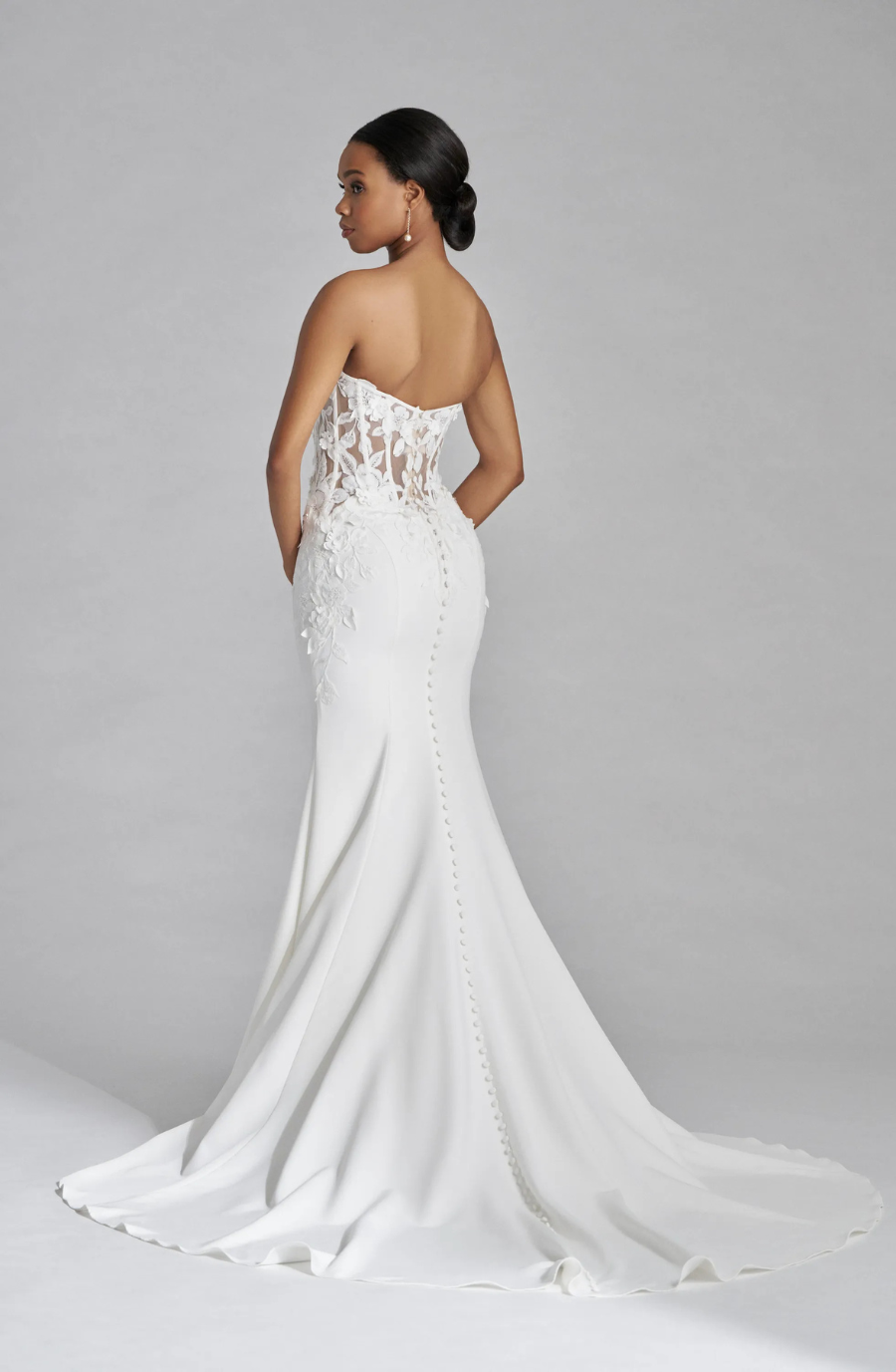 Model is wearing a strapless sweetheart fitted wedding gown with a gathered twist at the bodice 