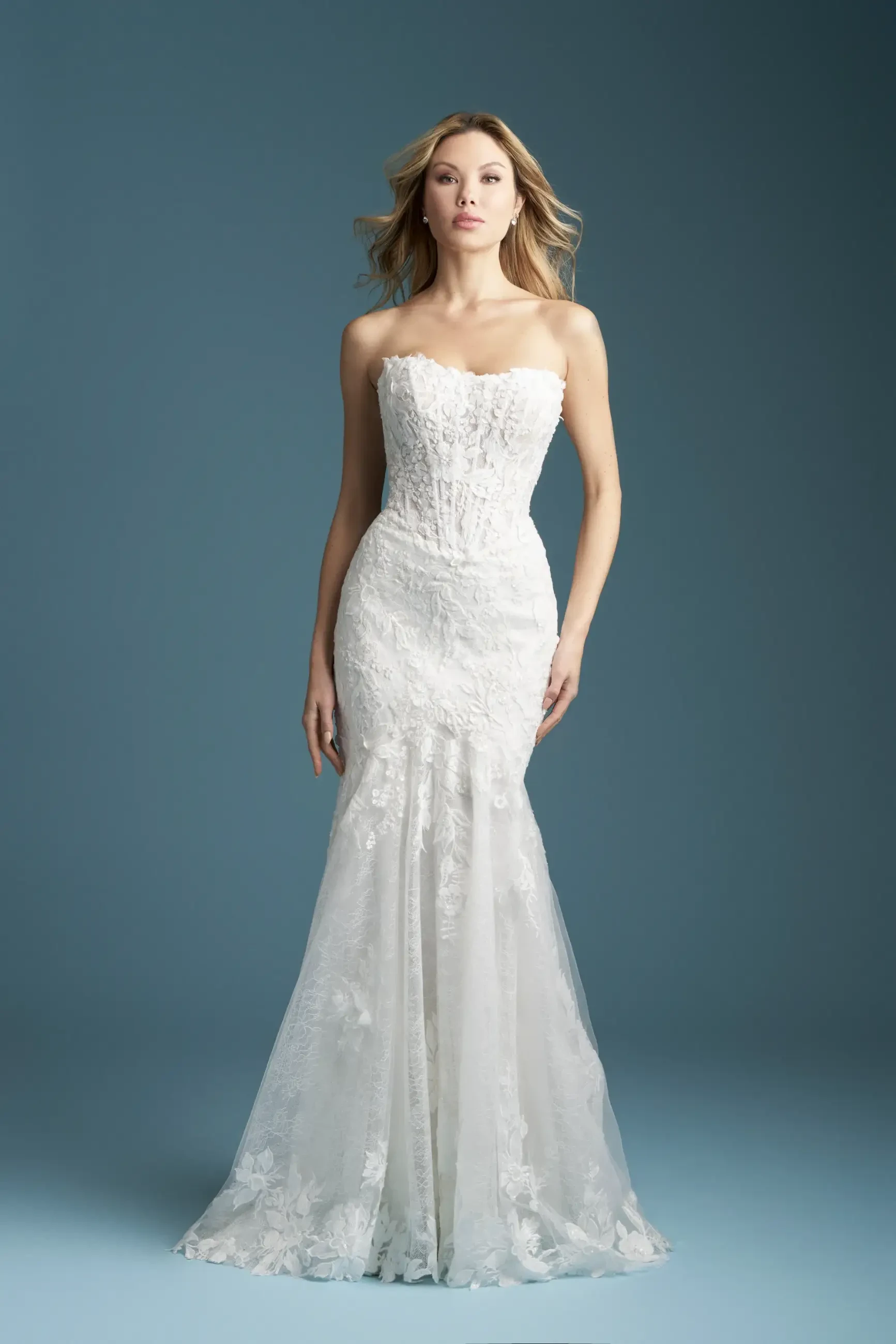 Model is wearing a sheath bridal gown with a basque waist and structured bodice with exposed boning