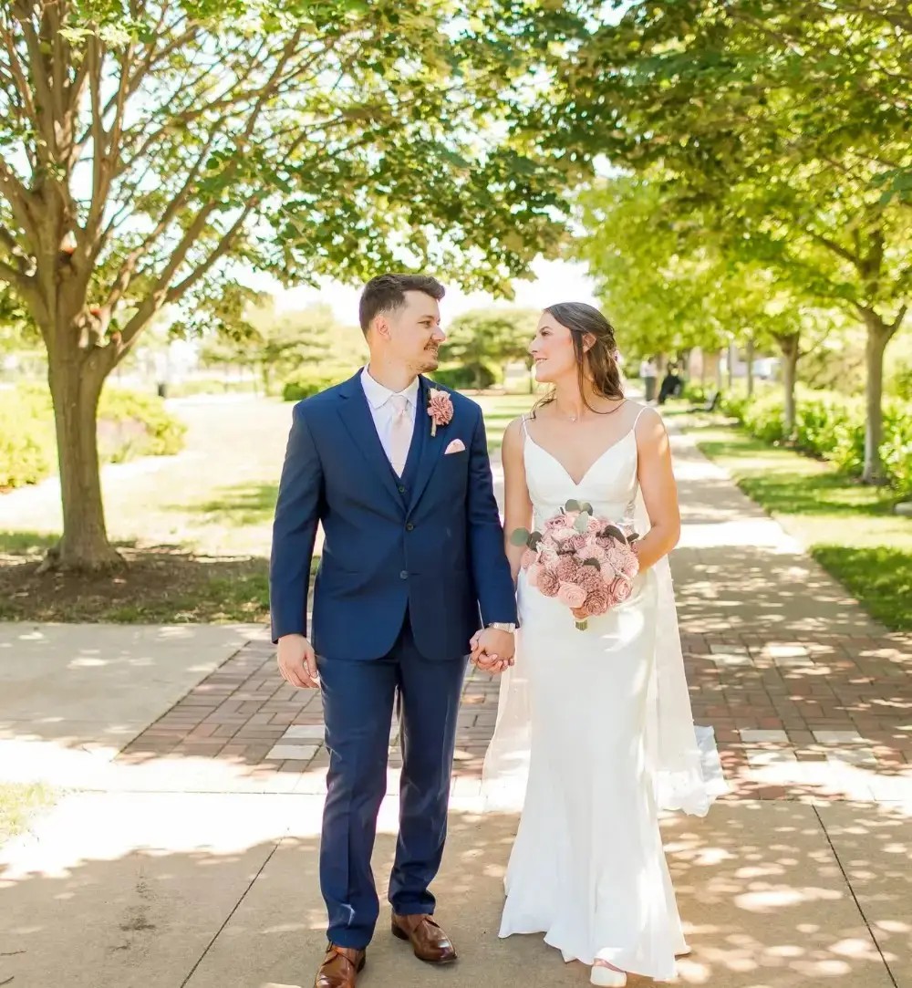 Image shows a married couple looking lovingly into each others eyes on their wedding day, woman in a minimalist wedding dress and man in a navy blue suit