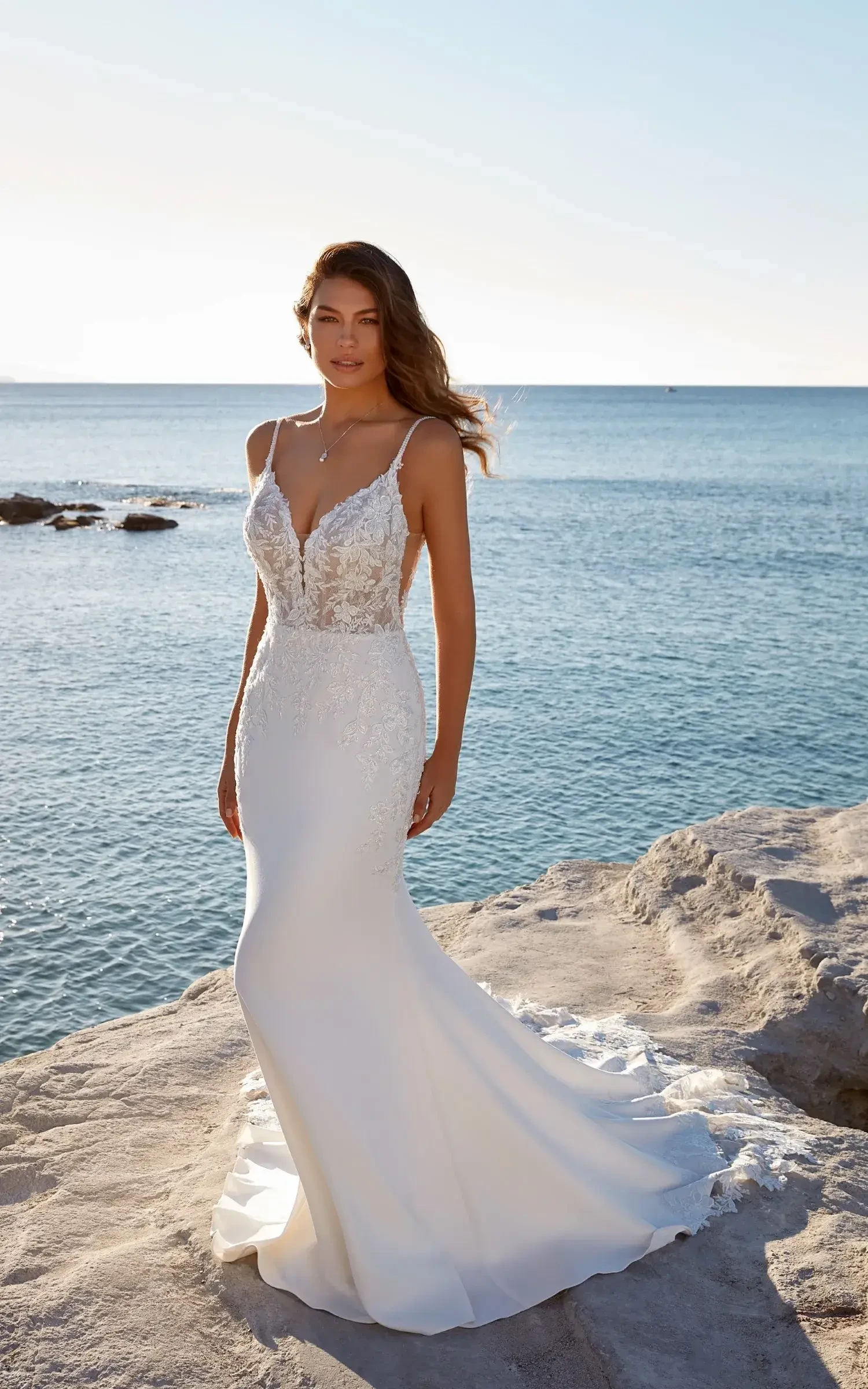 Model is wearing a sleeveless a-line wedding dress with spaghetti straps