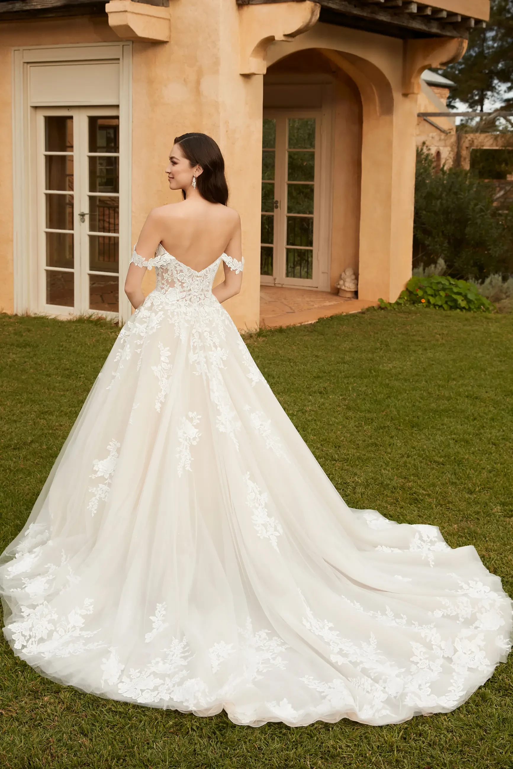 Model is wearing an off the shoulder lace ball gown by sophia tolli